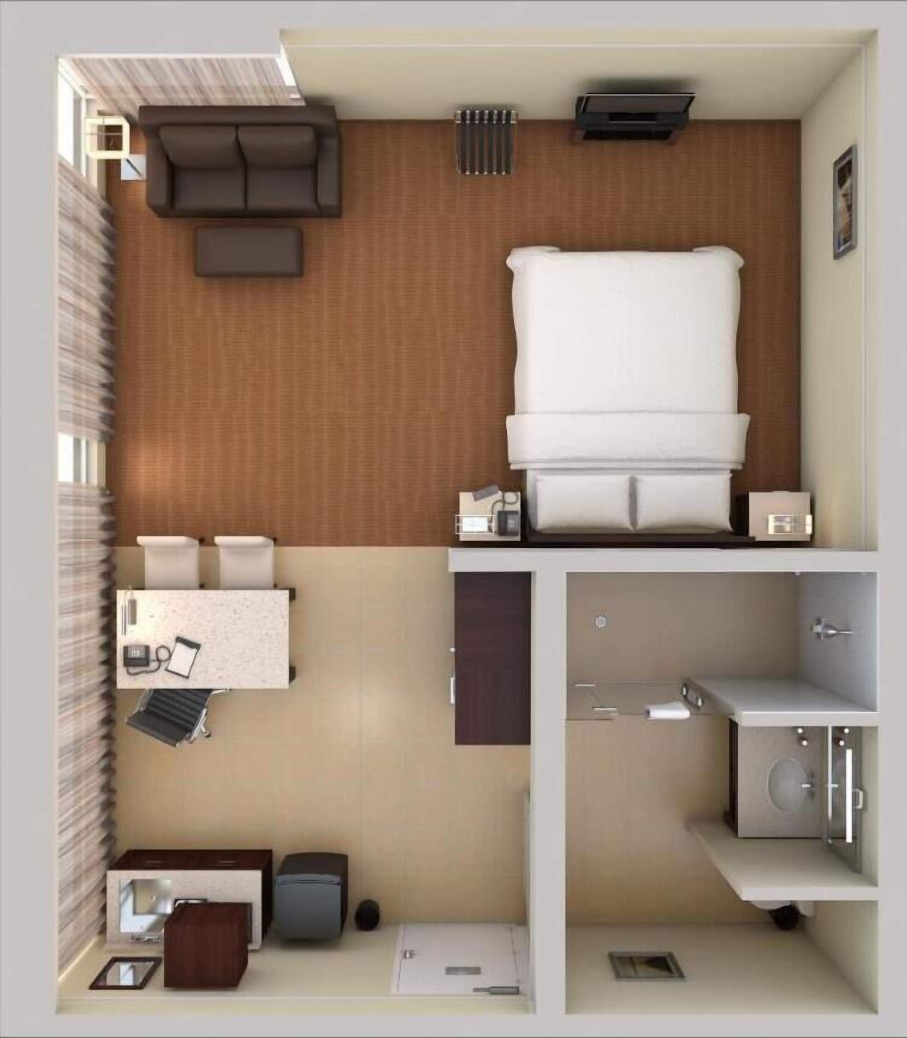 Ein kompaktes Hotelzimmer mit Bett, einer kleinen Sitzecke, einem Schreibtisch und einem Badezimmer.