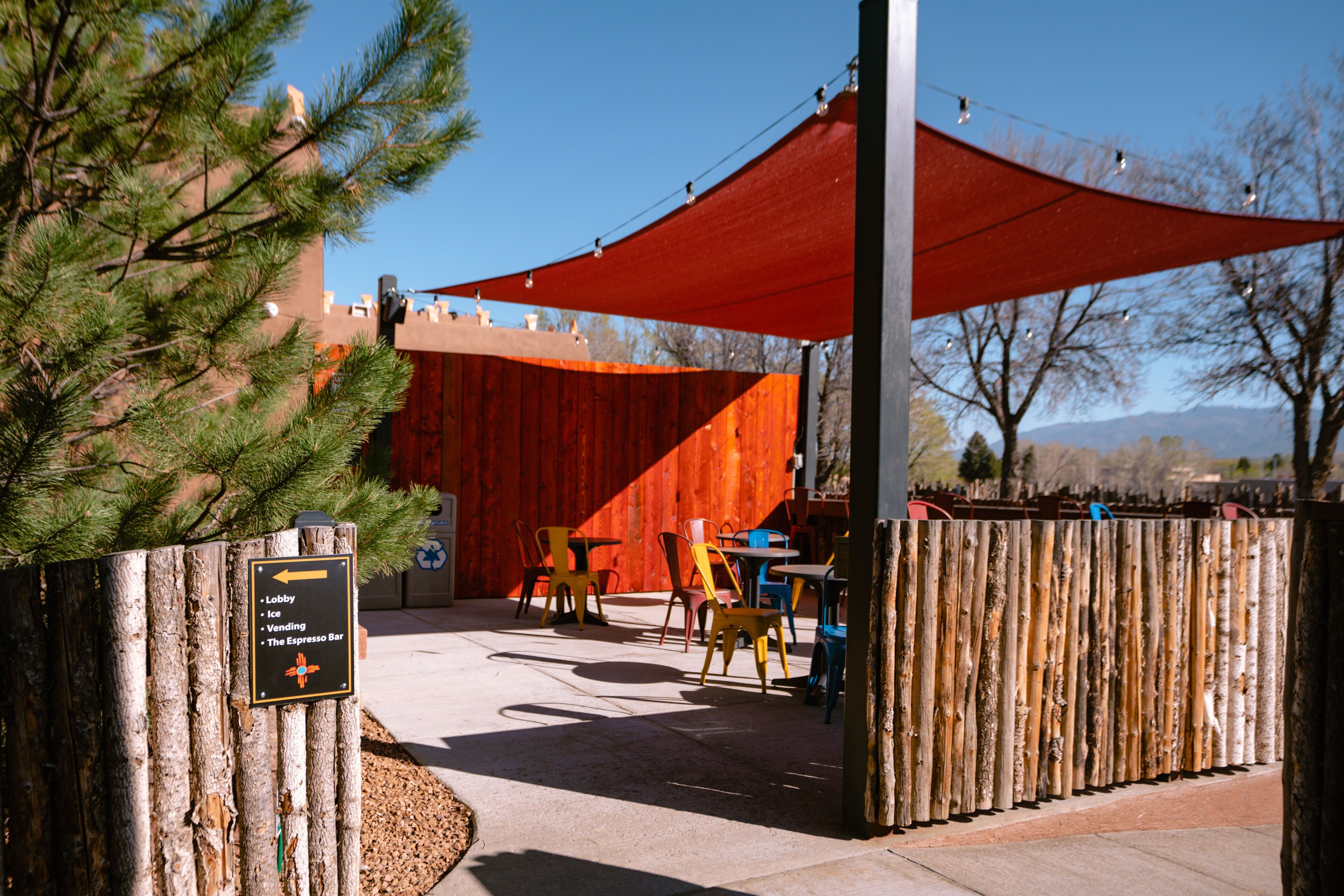 A patio area with outdoor seating, a directional sign, and a red canopy.