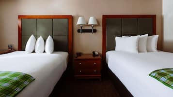 Een hotelkamer met twee bedden, een nachtkastje met een lamp en een kleine ladekast.