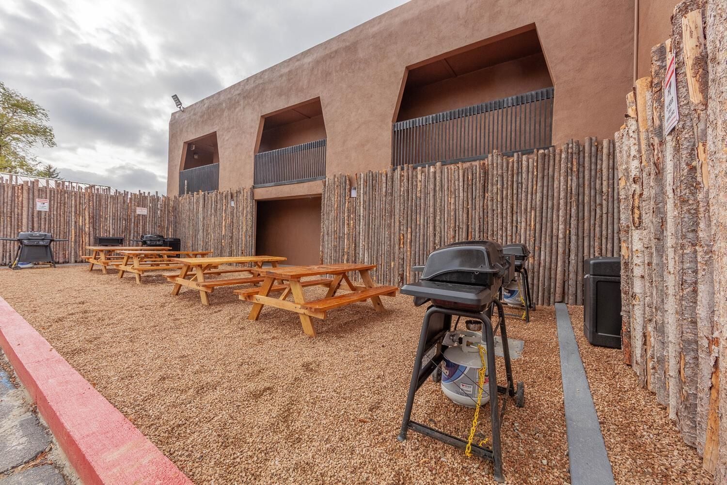 Un patio al aire libre con mesas de picnic y una parrilla.