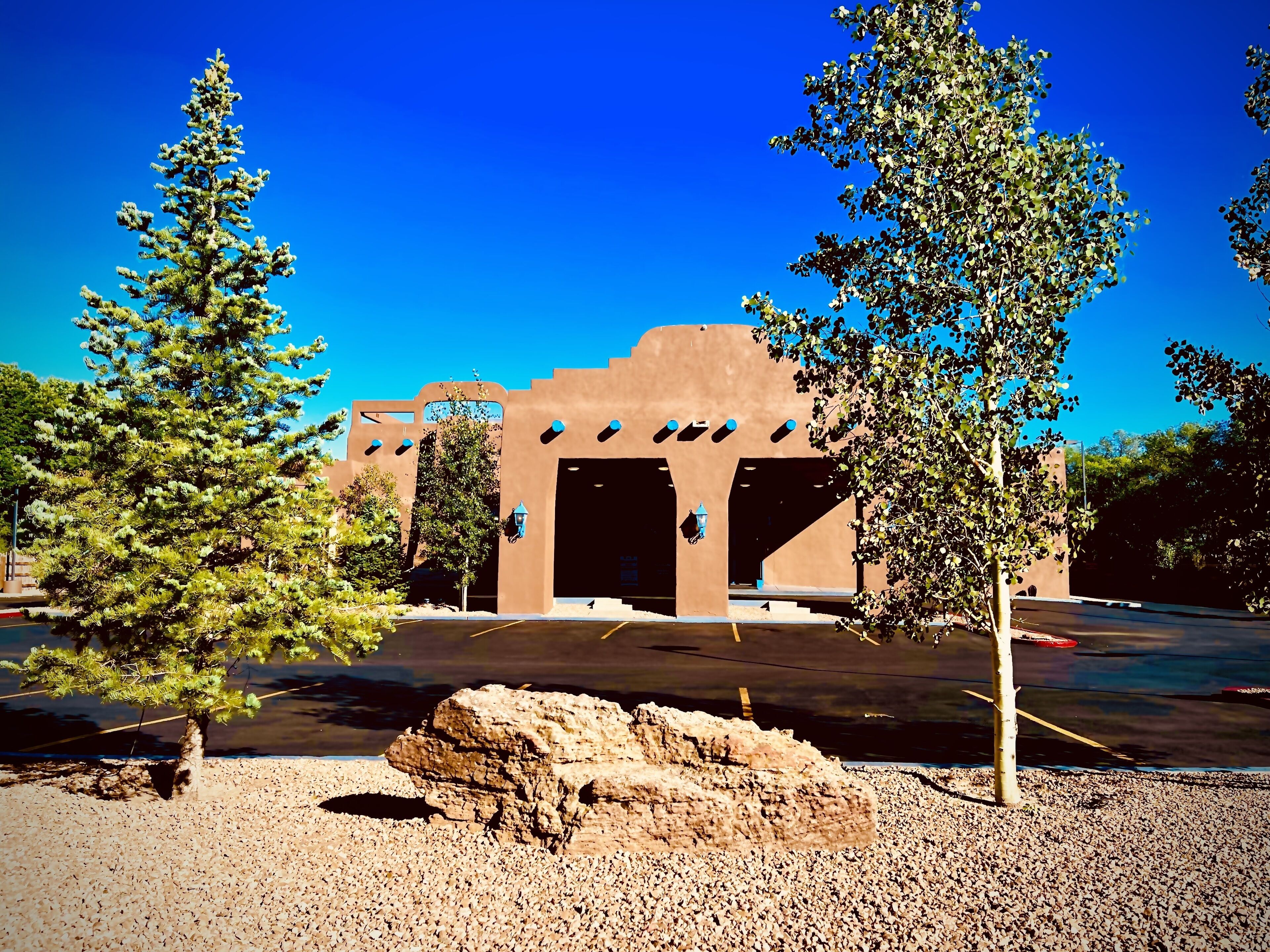 A building with a brown facade, multiple doorways, and a parking lot.