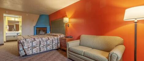 Una habitación de hotel con cama, sofá, lámpara y chimenea.