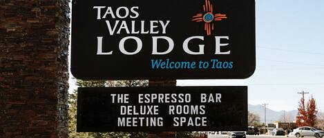 Taos Valley Lodge -hotellin kyltti, jossa mainitaan hotellin tarjoamat palvelut: espressobaari, ylelliset huoneet ja kokoustilat.