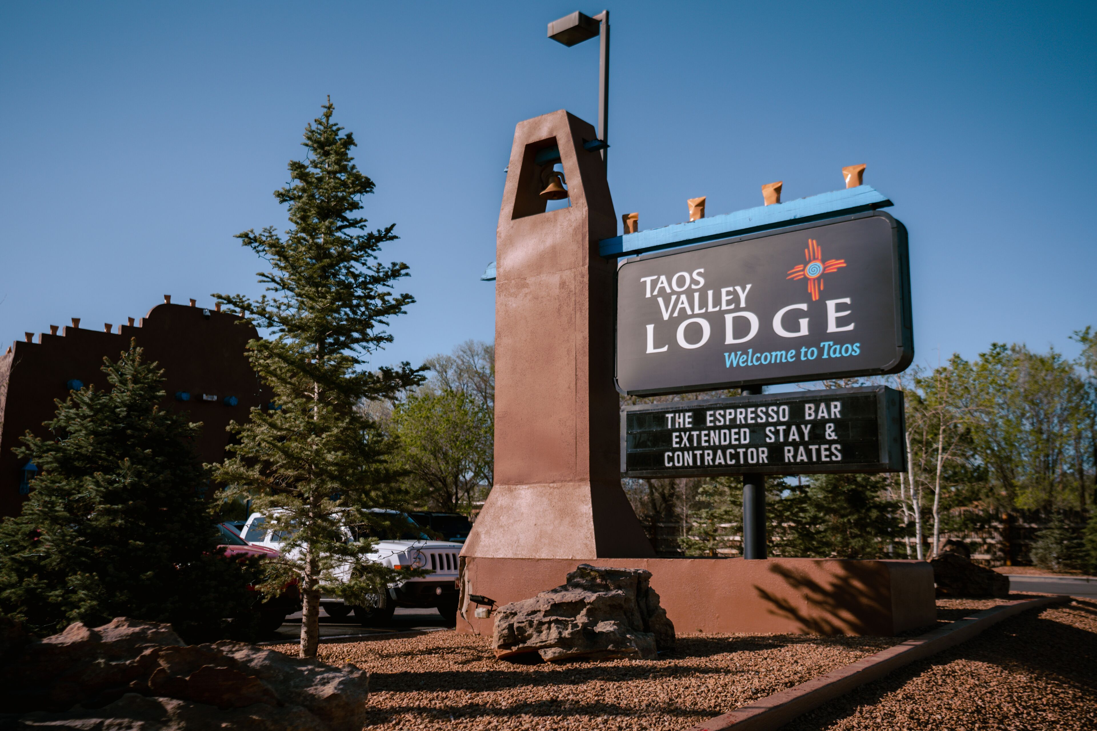 A sign for Taos Valley Lodge with a welcome message and mentions The Espresso Bar, extended stay, and contractor rates.