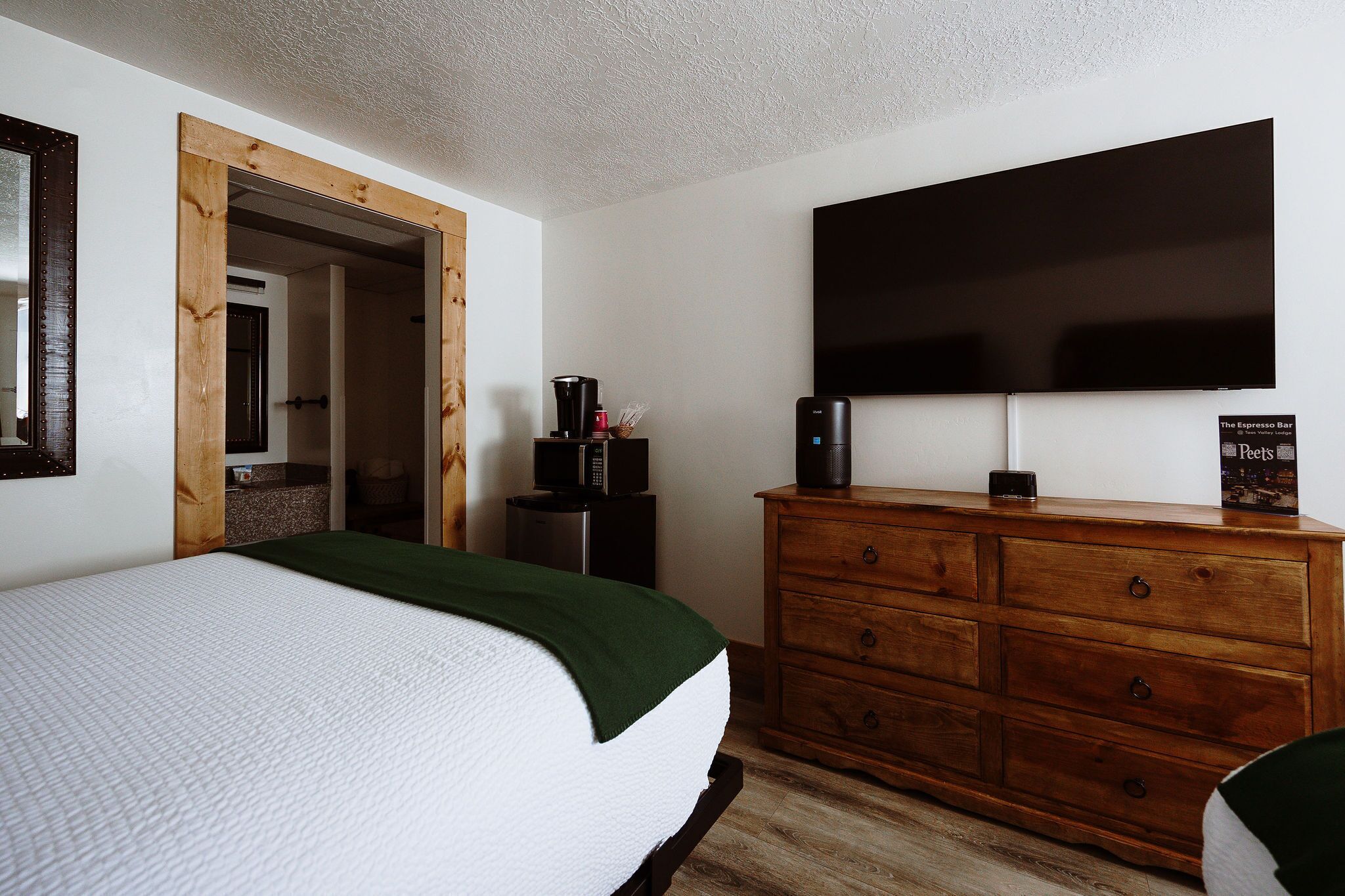Hotelkamer met een bed, een houten dressoir, een flatscreen televisie, een koffiezetapparaat en een bordje voor The Espresso Bar.