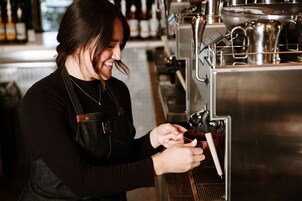Una persona usando una máquina de café en un entorno comercial.