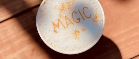Eine weiße Tasse mit dem Schriftzug 'MAGIC' auf einer Holzoberfläche.