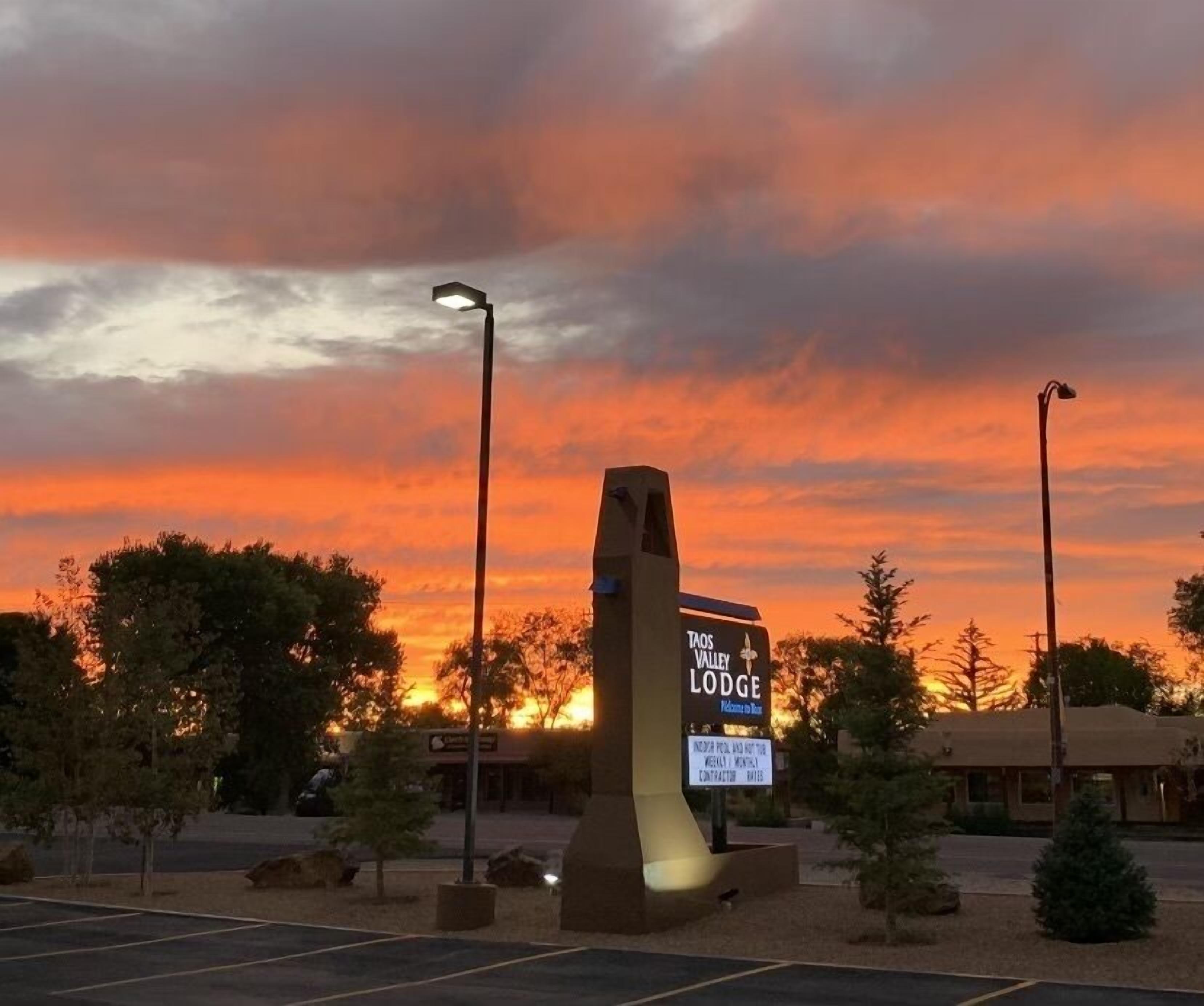 Señal de Taos Valley Lodge con un atardecer de fondo.