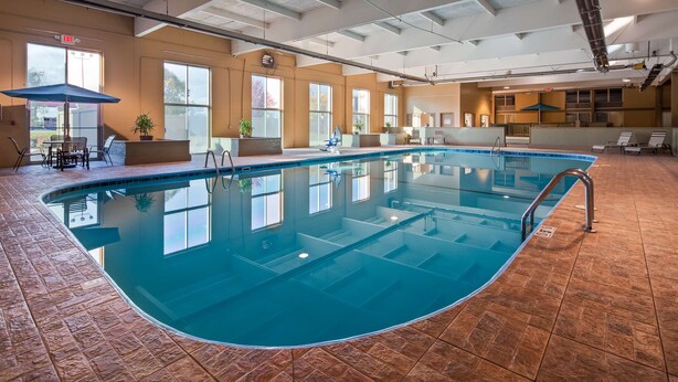 An indoor swimming pool with clear water, surrounded by tiled flooring and large windows. - Best Western Crossroads Of The Bluffs (Council Bluffs)