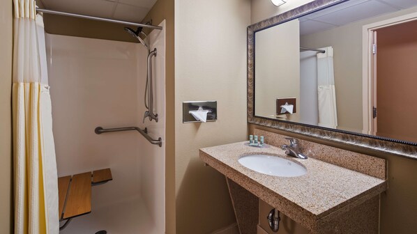 A bathroom with a shower, grab bars, a sink, and a mirror. - Best Western Crossroads Of The Bluffs (Council Bluffs)