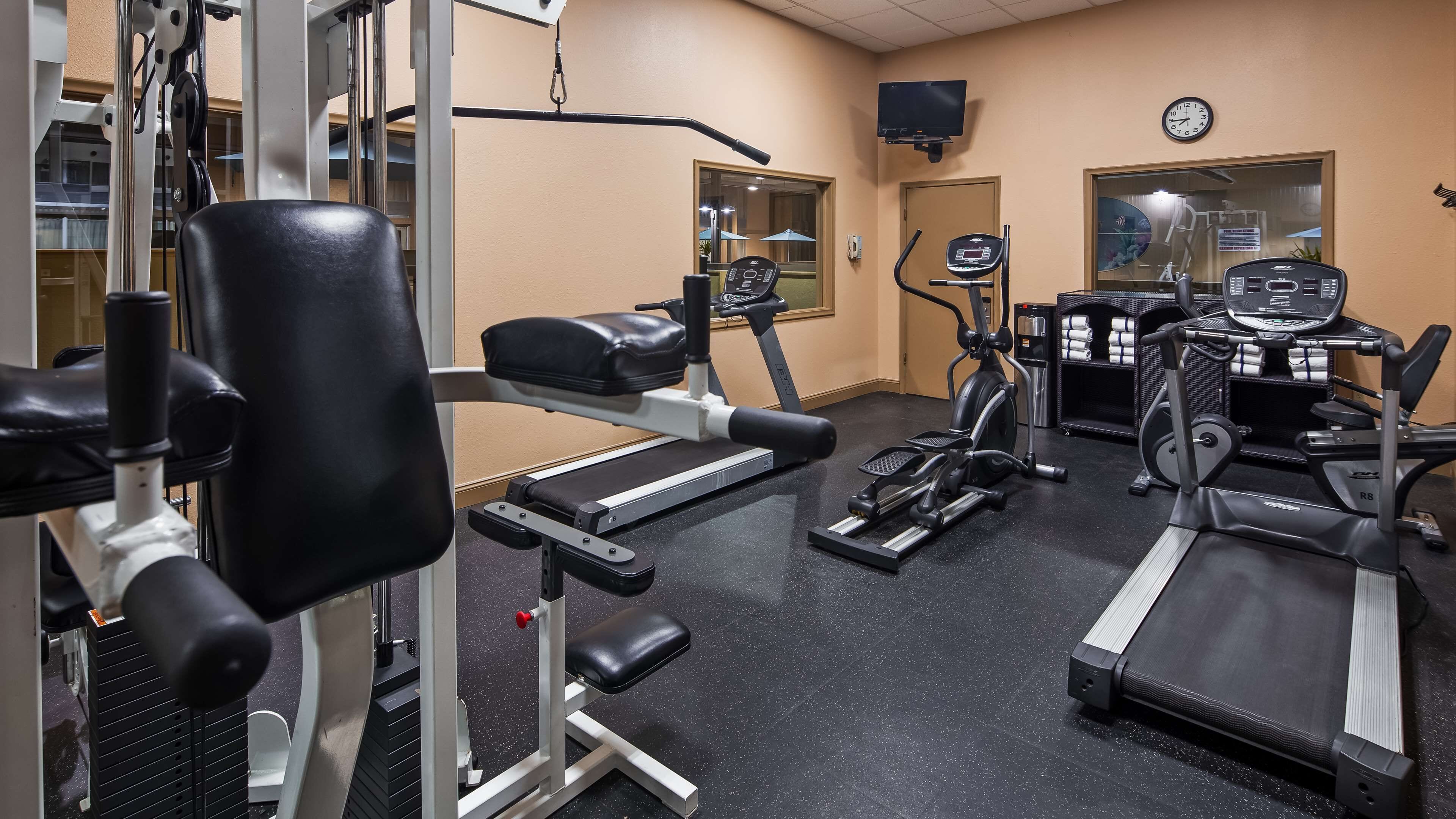 A gym with various exercise equipment including treadmills, an elliptical, and weight machines.