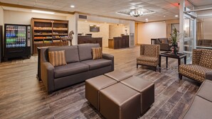 A hotel lobby with a sofa, armchairs, a coffee table, a vending machine, and a reception desk. - Best Western Crossroads Of The Bluffs (Council Bluffs)