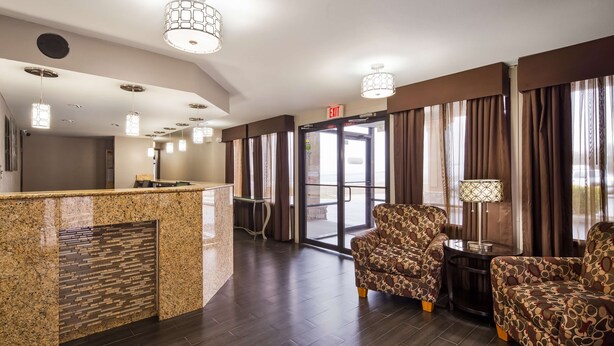 A hotel lobby with a reception desk, seating area, and a glass door leading outside. - Best Western Coachlight (Rolla)