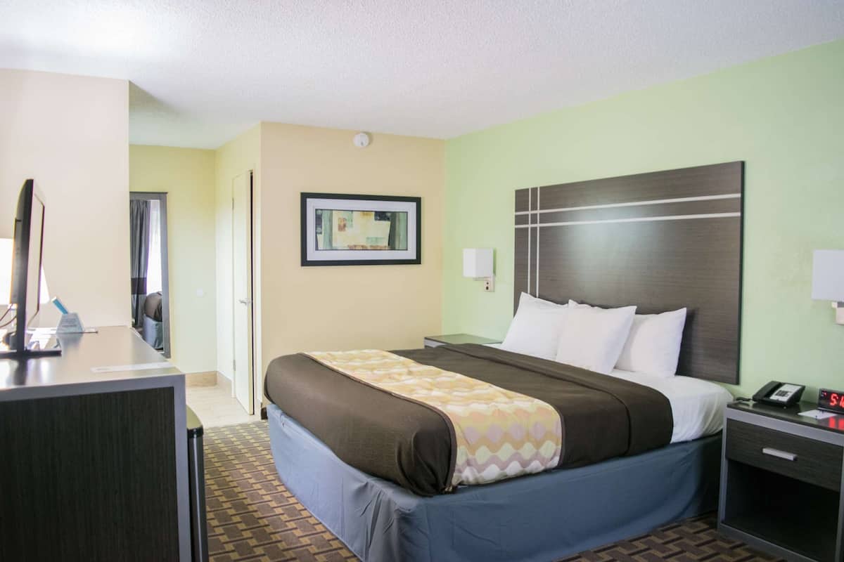 A hotel room with a bed, bedside table, and a desk with a computer.