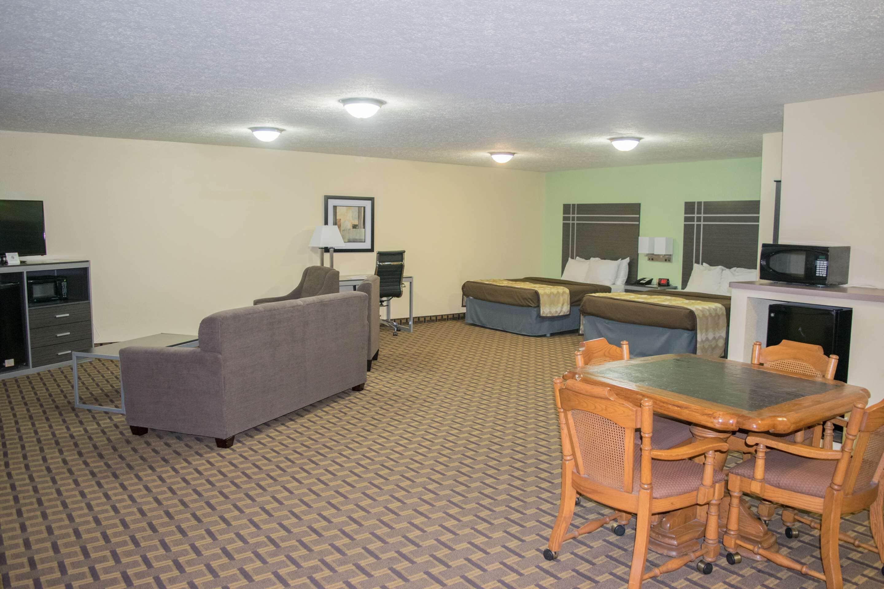 Una habitación de hotel con sofá, cama, mesa de comedor con sillas, televisión y microondas.