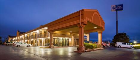 A hotel with a covered entrance, multiple rooms, and a parking lot.