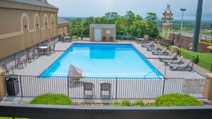 A swimming pool with lounge chairs and a small building, surrounded by a fence and greenery. - Best Western Coachlight (Rolla)