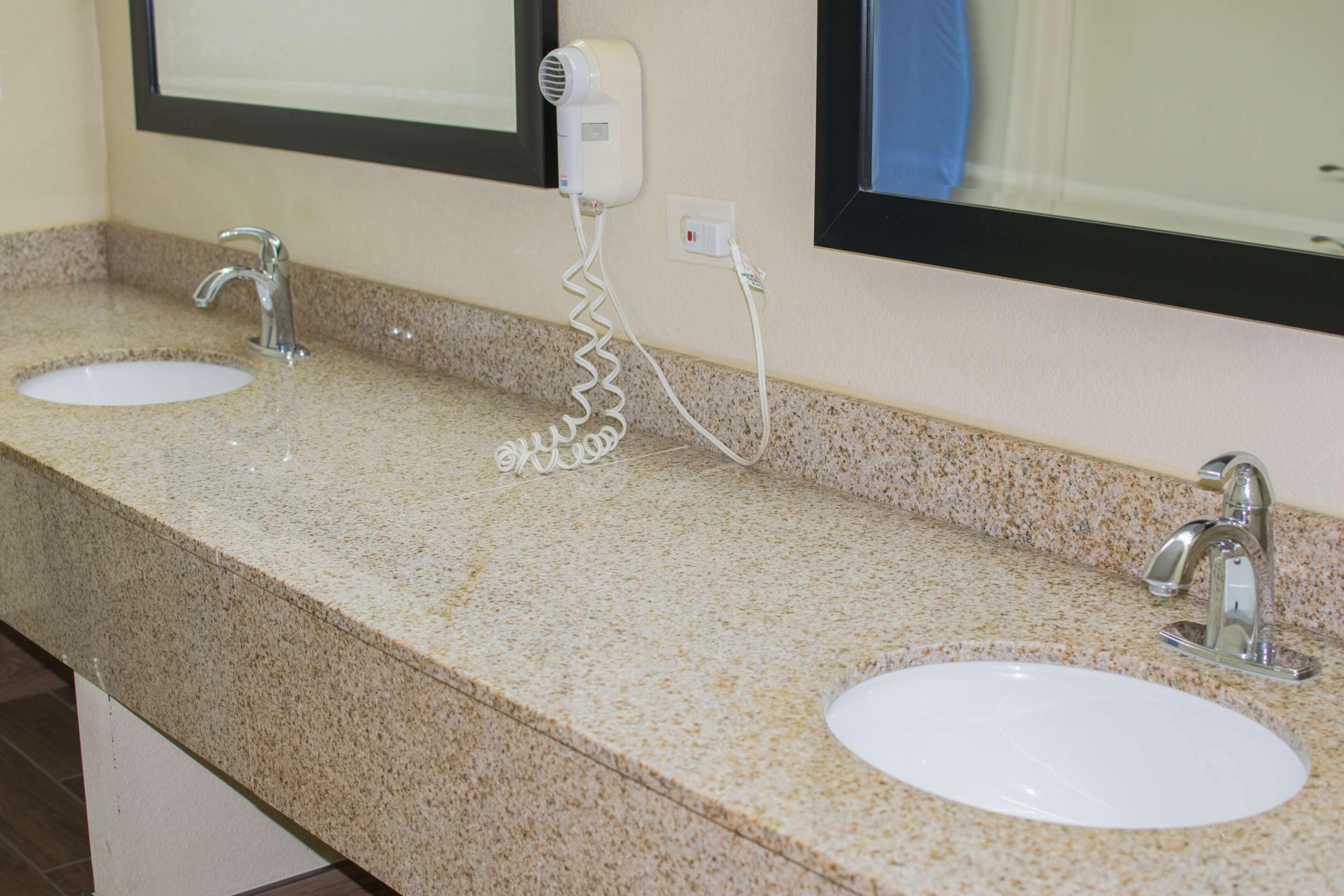 A bathroom with two sinks, a hair dryer, and a mirror.