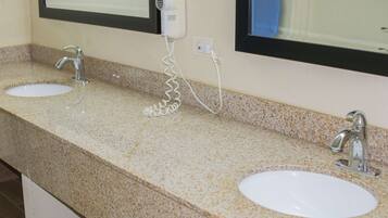 A bathroom with two sinks, a hair dryer, and a mirror.