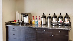 Een kitchenette met een koffiezetapparaat, koffiehoeveelheden en een Bunn koffiezetapparaat.