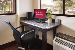 Un espace de travail équipé d’un ordinateur de bureau, d’une chaise et d’un panneau indiquant que le Wi-Fi est disponible gratuitement.