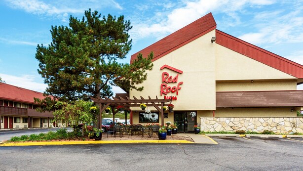 Een Red Roof Inn met een rood dak, beige gevel en een overdekt terras met plantenpotten.