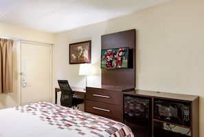 Ein Hotelzimmer mit Bett, Schreibtisch mit Stuhl, Fernseher und Mikrowelle.