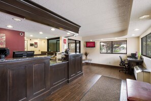 A hotel reception area with a dark wood reception desk, a flat-screen TV, and a sign indicating free Wi-Fi availability.