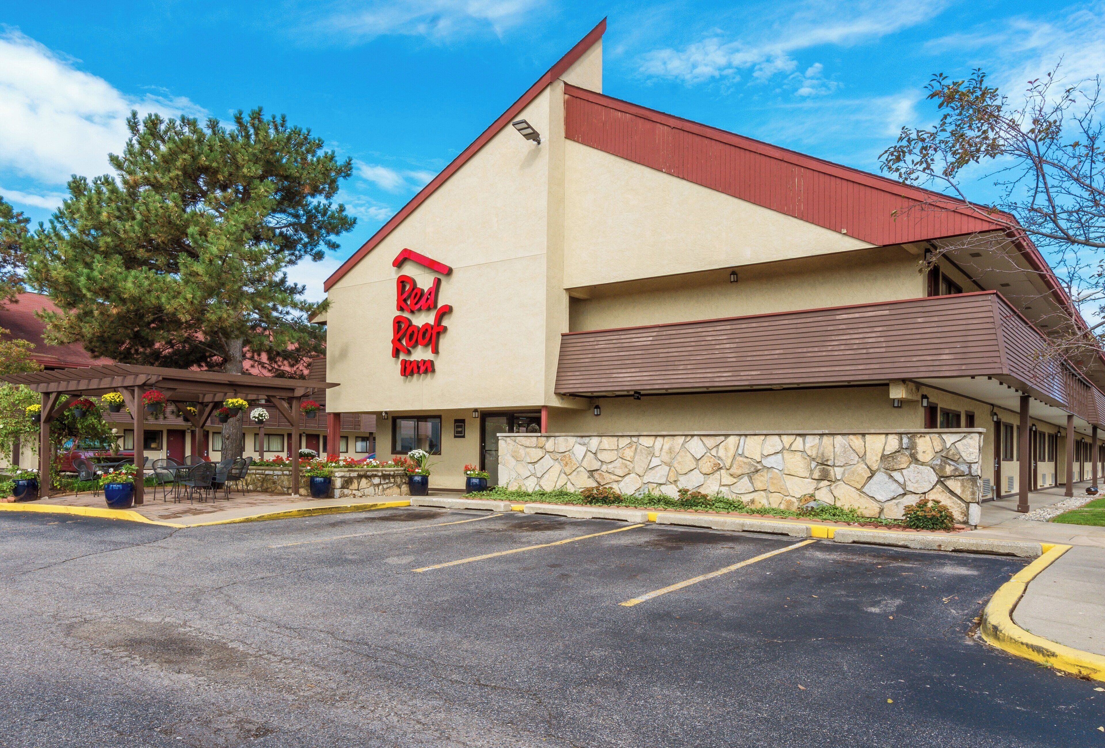 A Red Roof Inn with a stone facade, outdoor seating, and a parking lot.