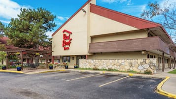 A Red Roof Inn with a stone facade, outdoor seating, and a parking lot.