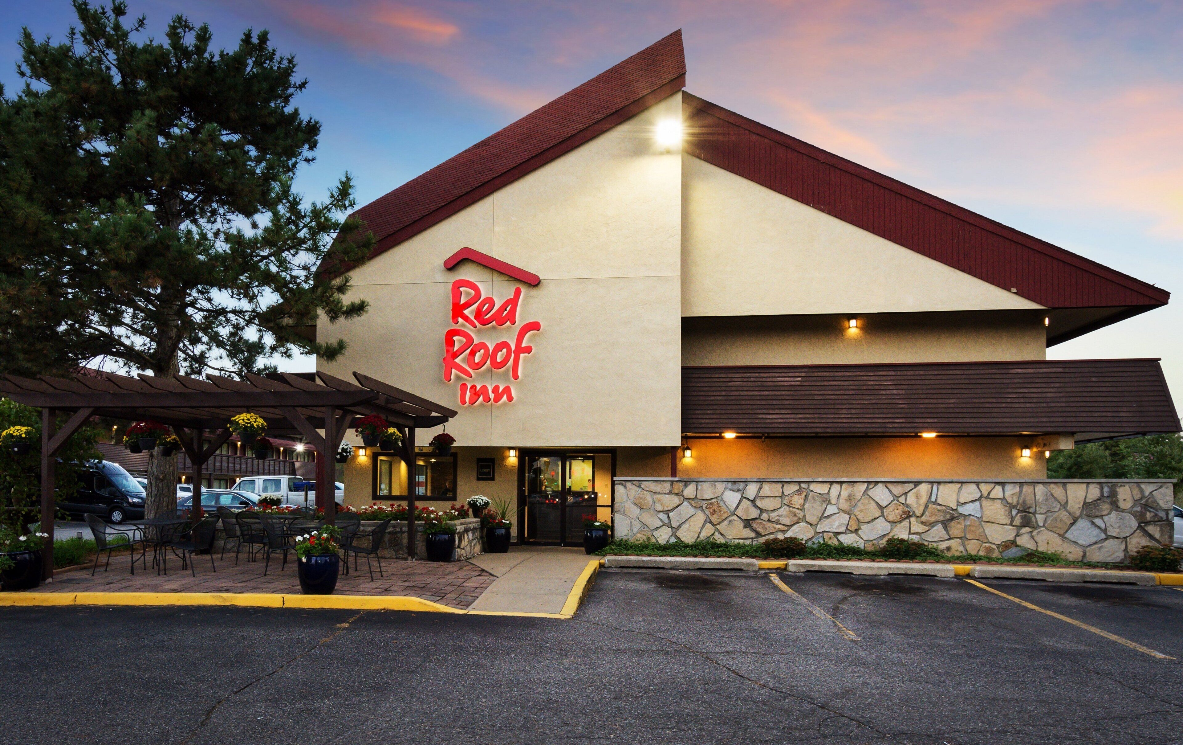 A Red Roof Inn with a stone facade, outdoor seating, and a parking lot.