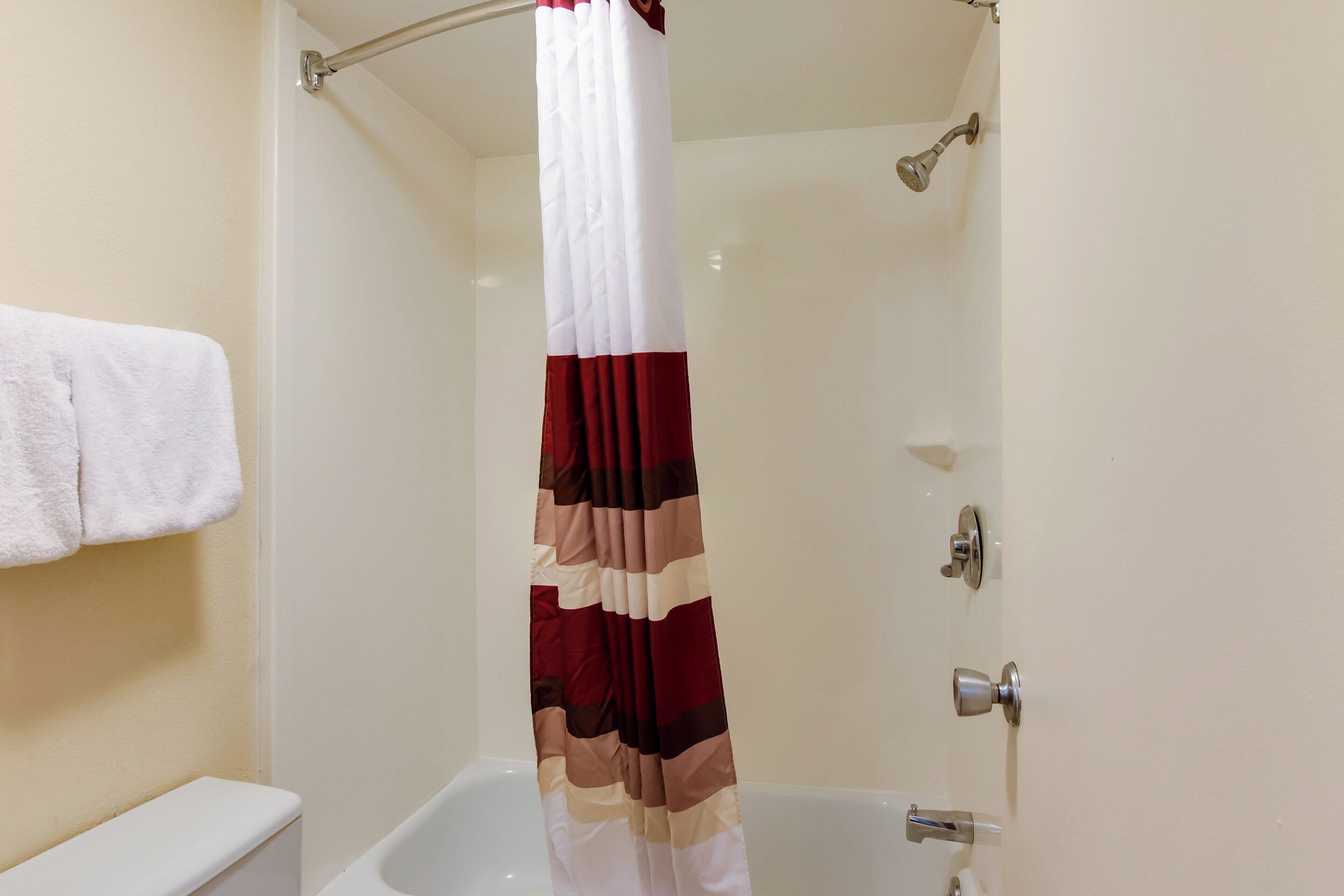 Un baño con una bañera blanca, cortina de ducha y un perchero.