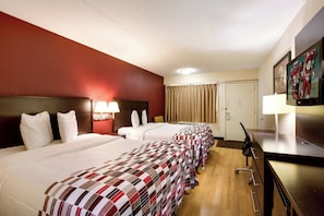 A hotel room with three beds, a desk, a television, and a window with curtains. - Red Roof Inn Grand Rapids Airport (Grand Rapids)