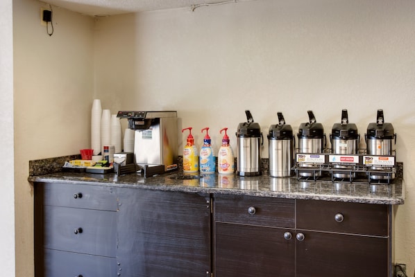 A kitchen counter with a coffee machine, hot water dispensers, and various beverage dispensers. - Red Roof Inn Grand Rapids Airport (Grand Rapids)