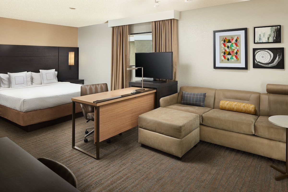 A hotel room with a bed, a desk, a sofa, and a television.
