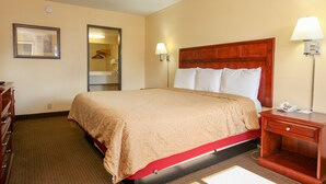 A hotel room with a bed, bedside lamps, a nightstand, a dresser, and a framed picture on the wall.