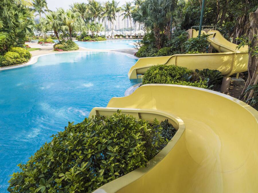 A resort pool with a water slide and lush greenery.