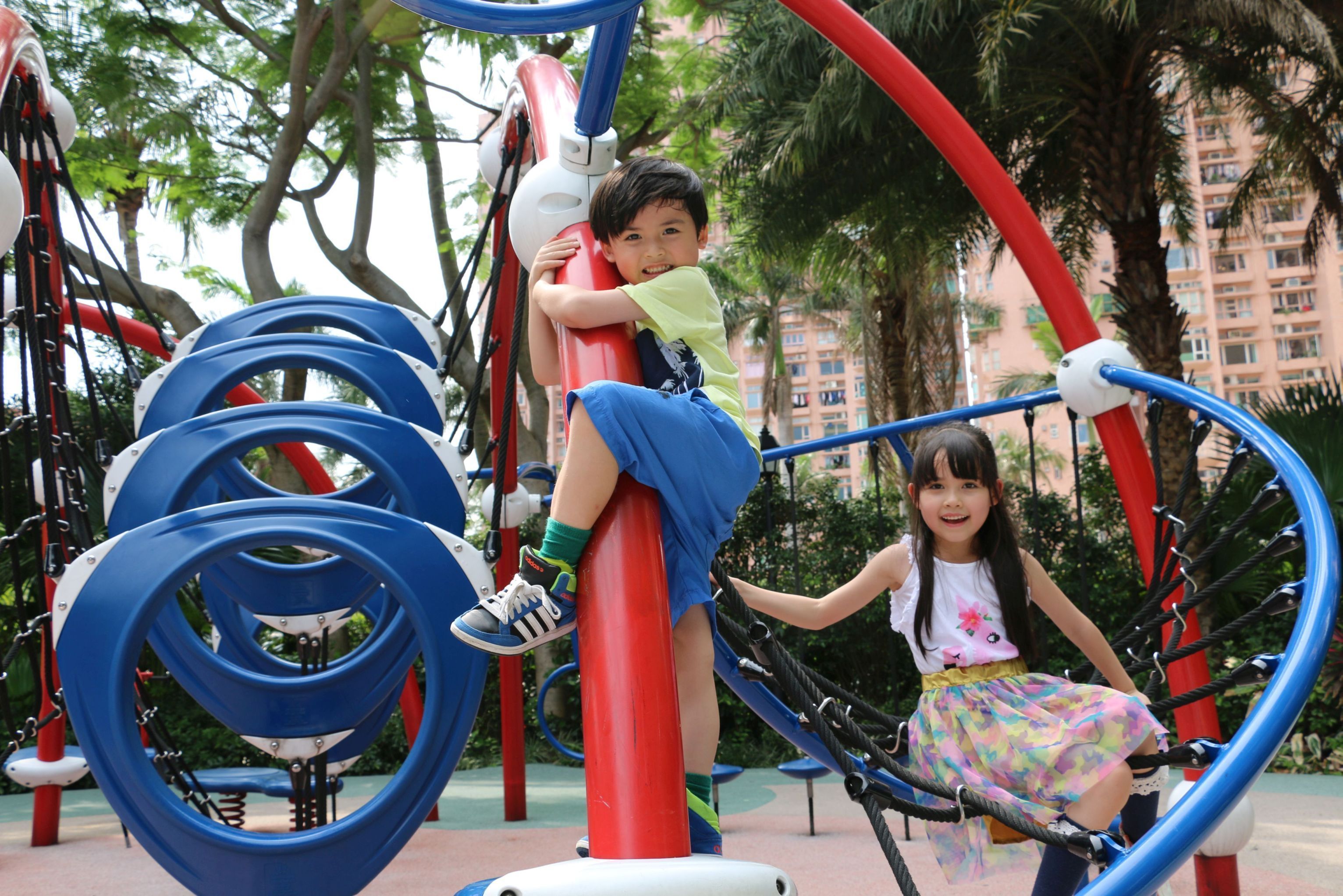 A playground with a red and blue climbing structure.