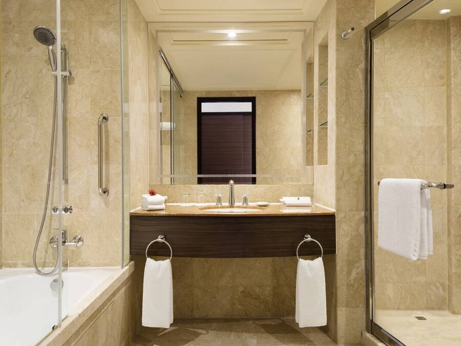 A modern bathroom with a bathtub, a glass-enclosed shower, a vanity with a mirror, and two towel rings.