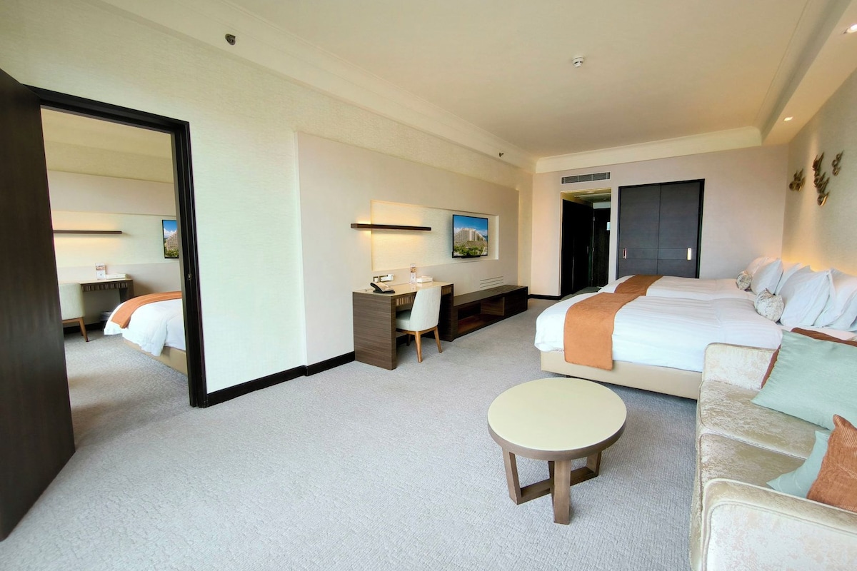 Une chambre d’hôtel comprenant un lit, un bureau, une chaise, une table ronde et un grand miroir.