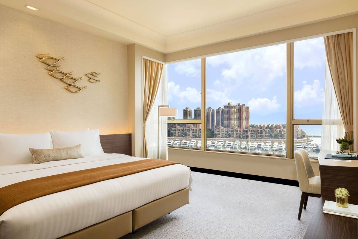Une chambre d’hôtel avec un grand lit, un bureau et une vue sur le paysage urbain.