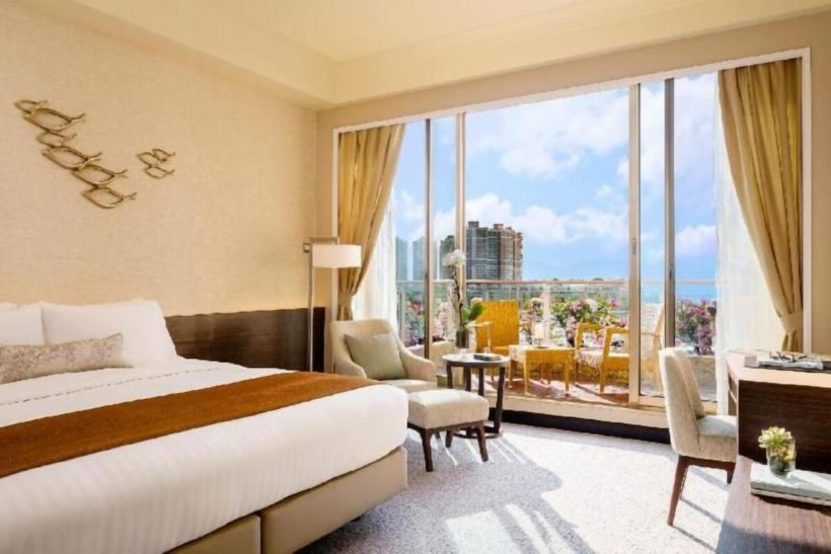 Une chambre d’hôtel avec un grand lit, un bureau, une chaise et une vue sur le paysage urbain.
