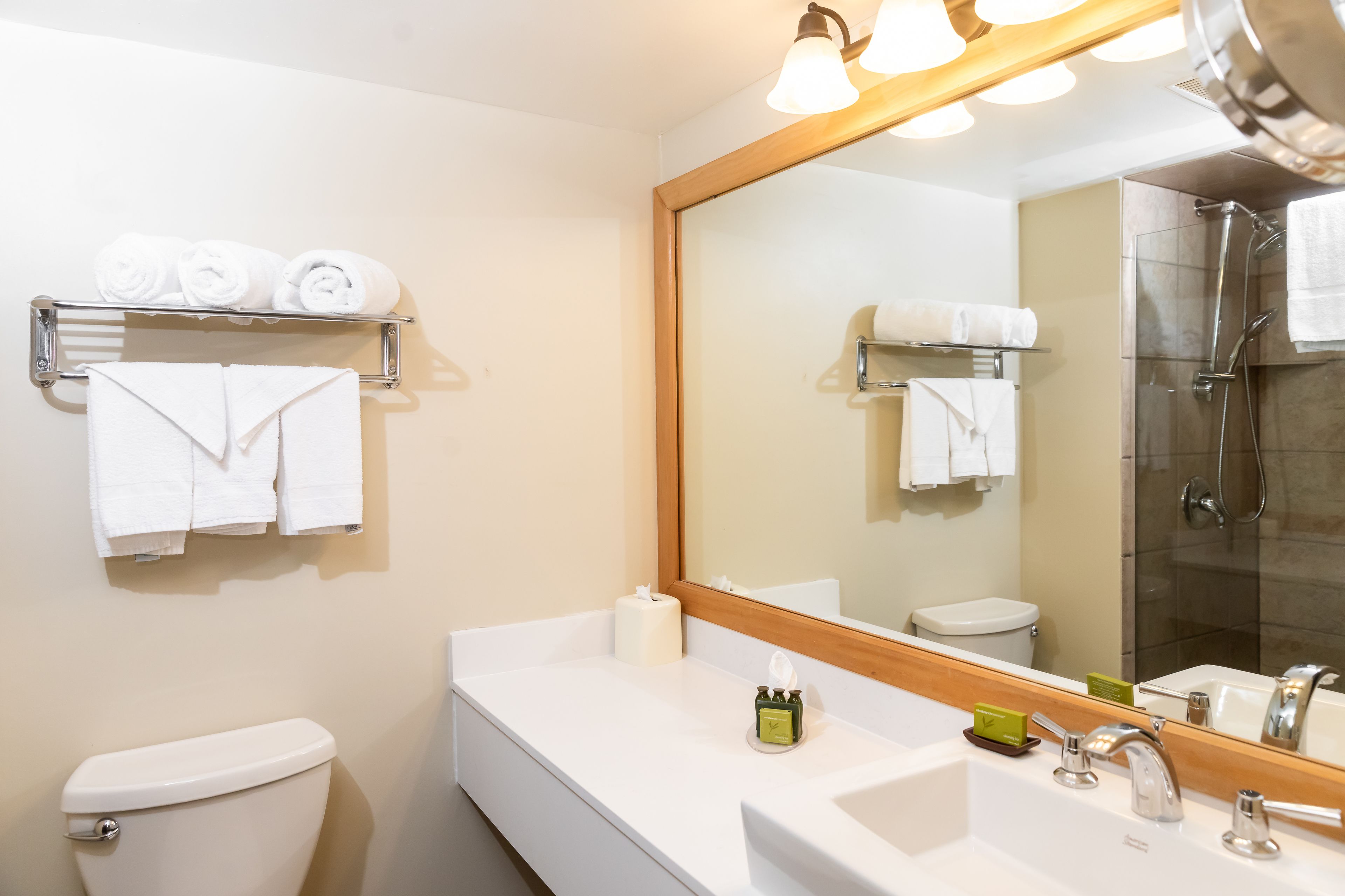 Un bagno moderno con un lavandino bianco, uno specchio grande e una cabina doccia in vetro.