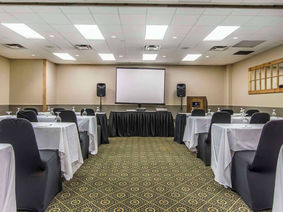 A conference room with tables, chairs, a projector screen, and speakers.