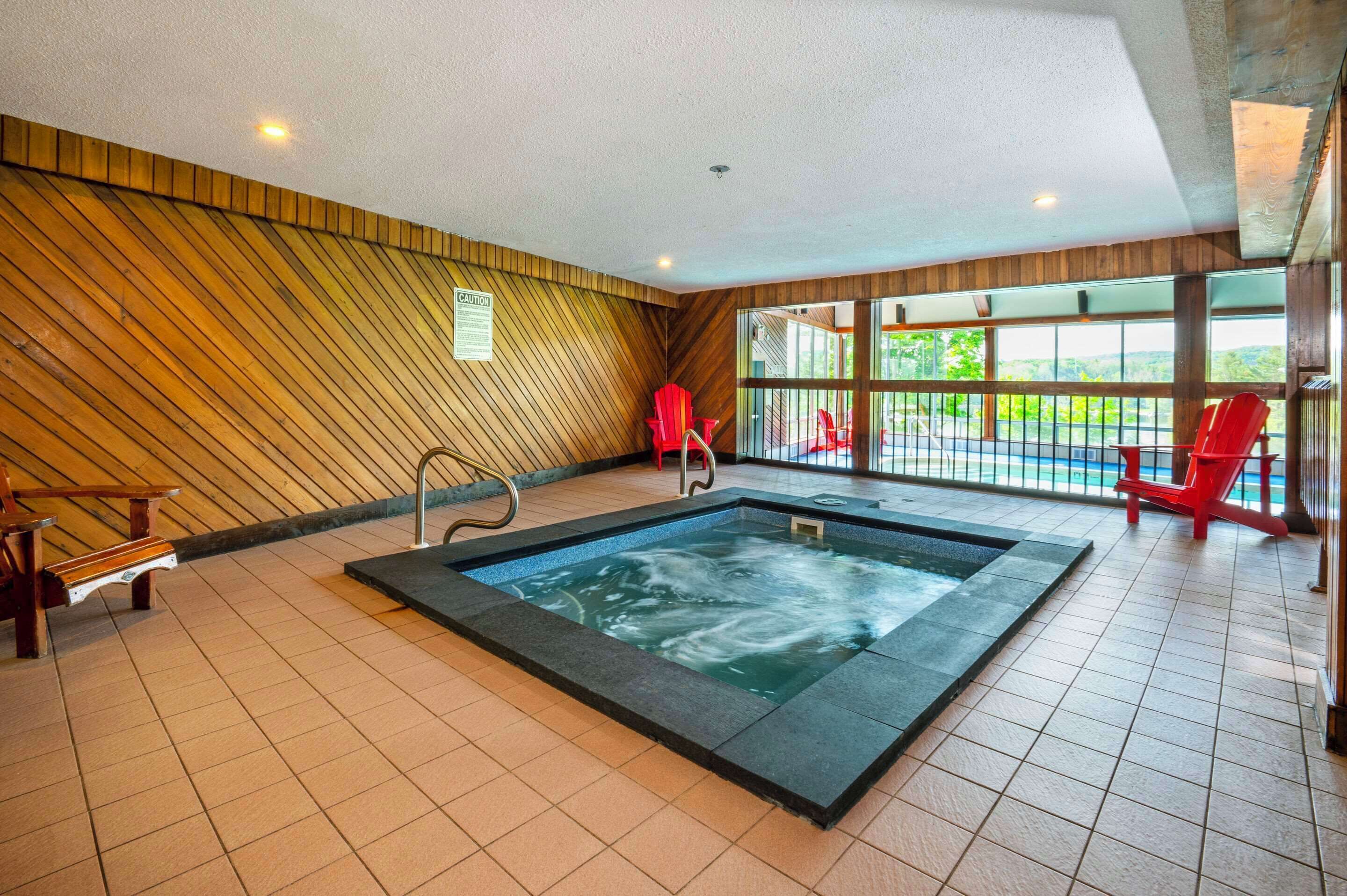 A spa area with a hot tub, wooden panel walls, and red chairs.