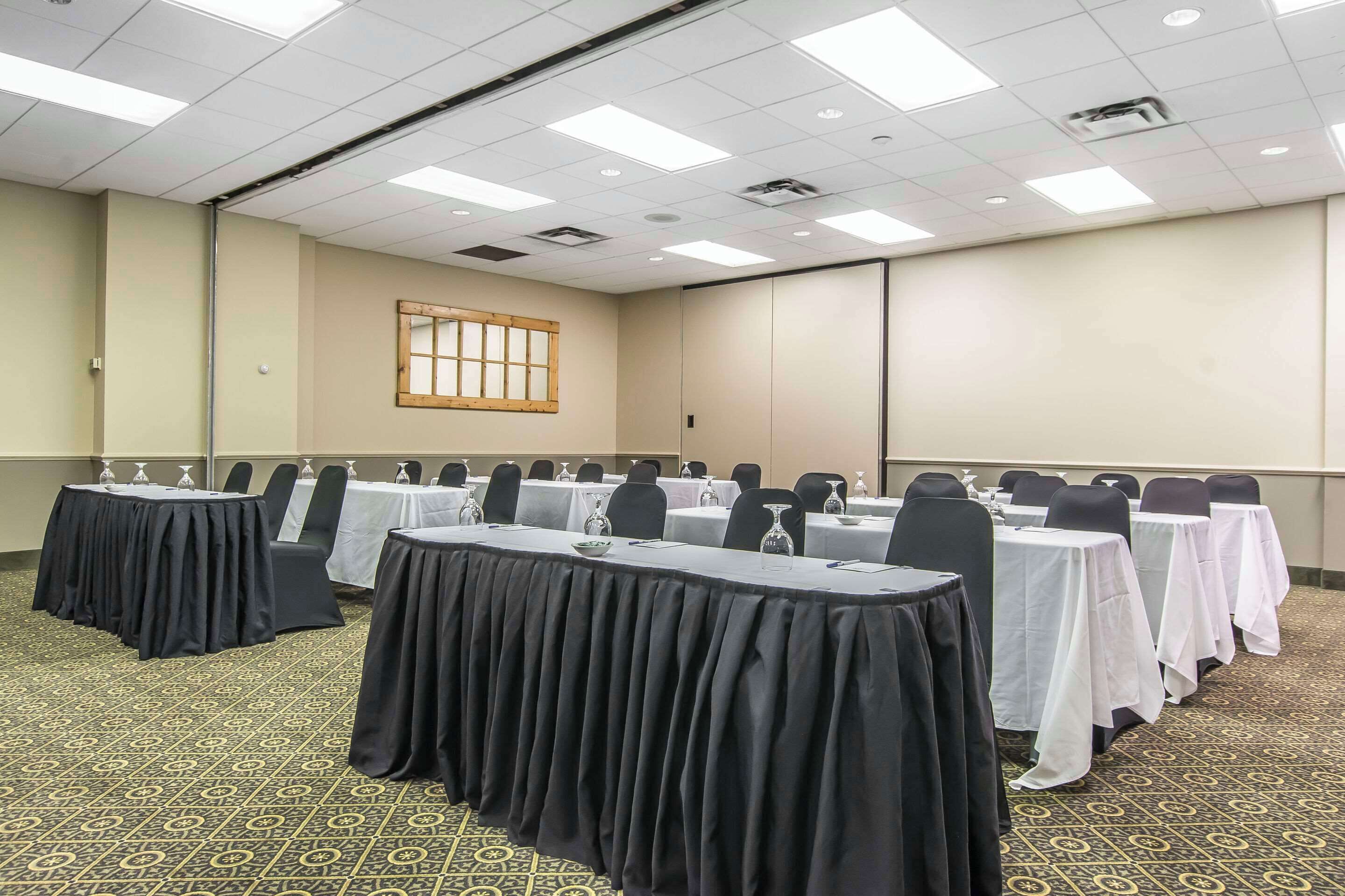 Une salle de conférence avec des tables disposées pour une réunion, équipée de plaques nominatives et de verres à eau.