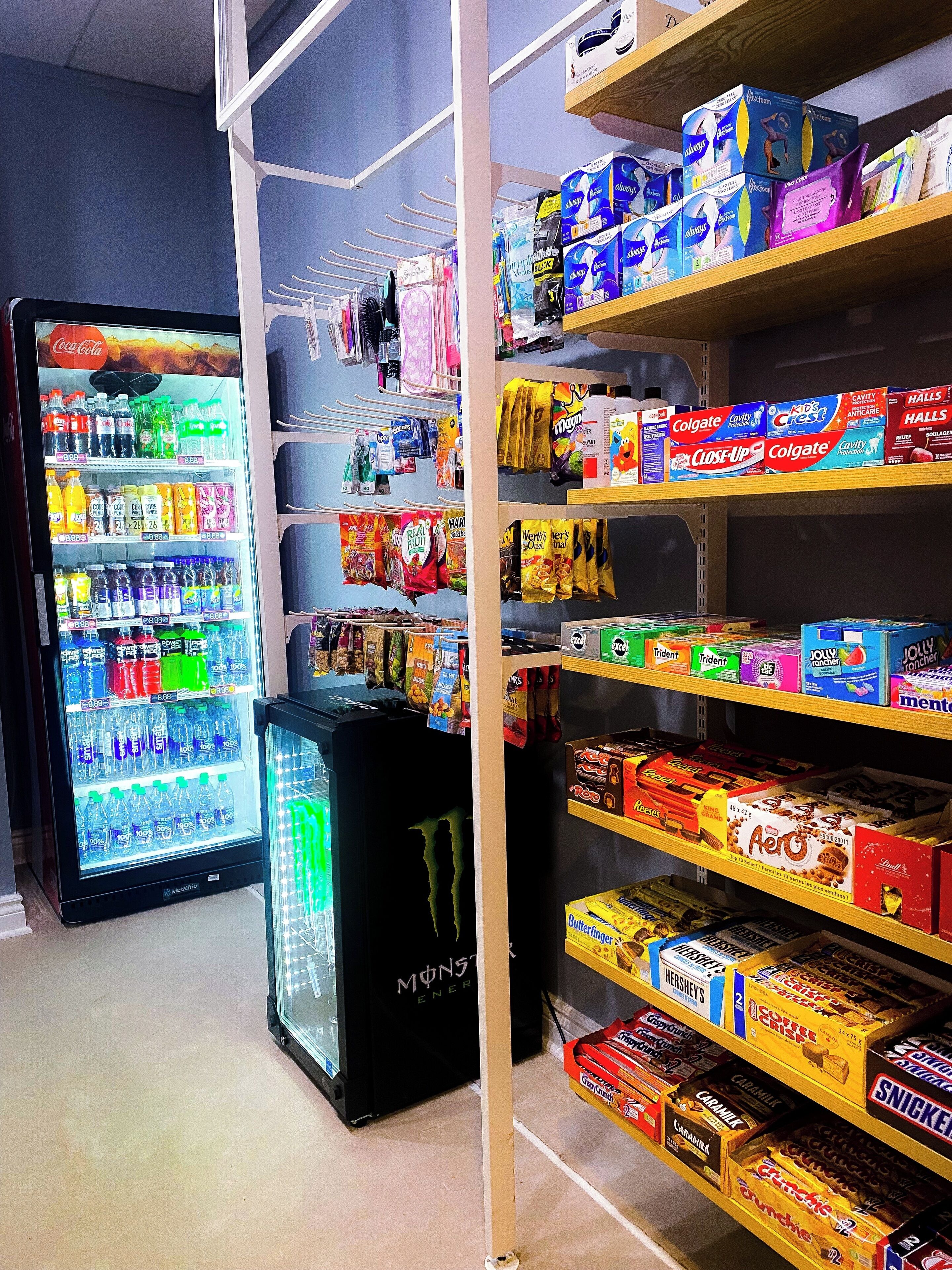 Una tienda con estantes repletos de diversos productos, entre ellos aperitivos, bebidas y artículos de cuidado personal.