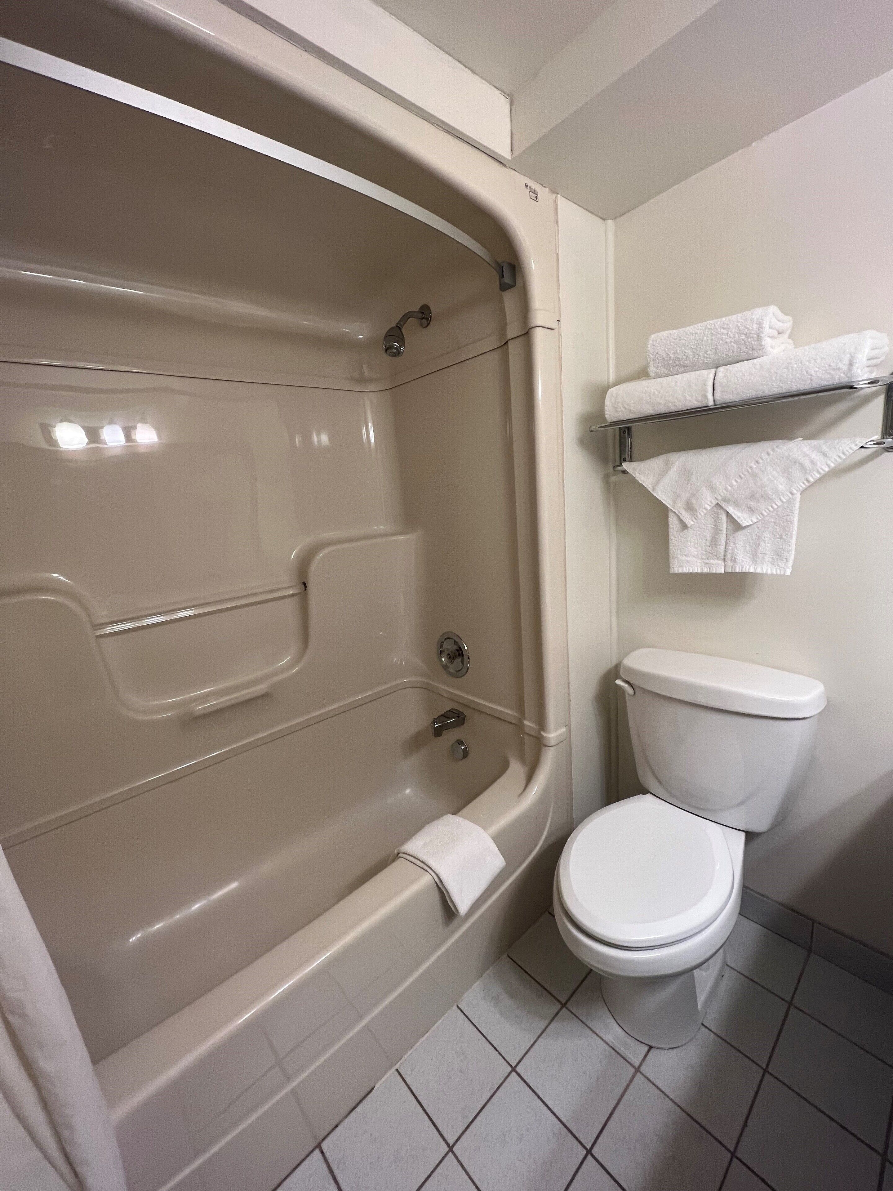 A bathroom with a bathtub, toilet, and towel rack.