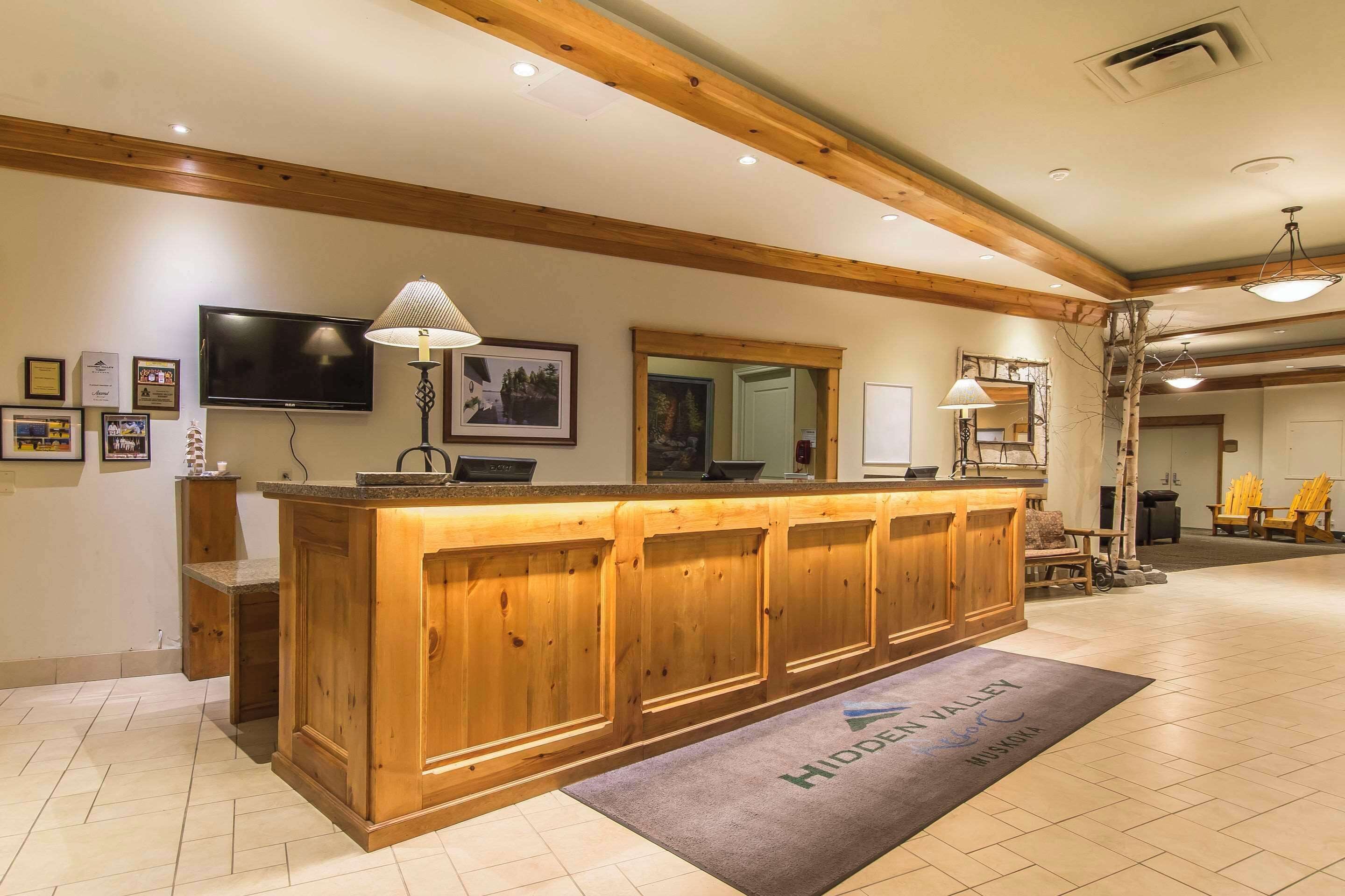 A reception area with a wooden counter, a television, framed pictures, and a sign reading "Hidden Valley."