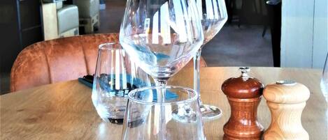 Una mesa con tres copas de vino y dos saleros y pimenteros.